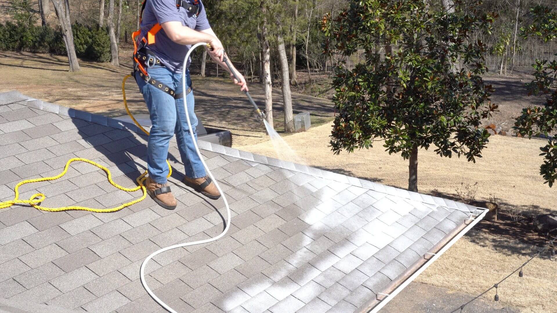 A man power washing a roof