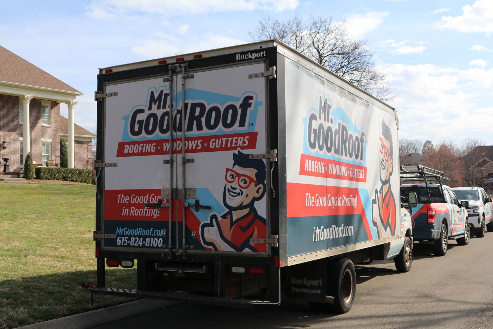 Two men in a white van that is covered in graphics for Mr Good Roof.