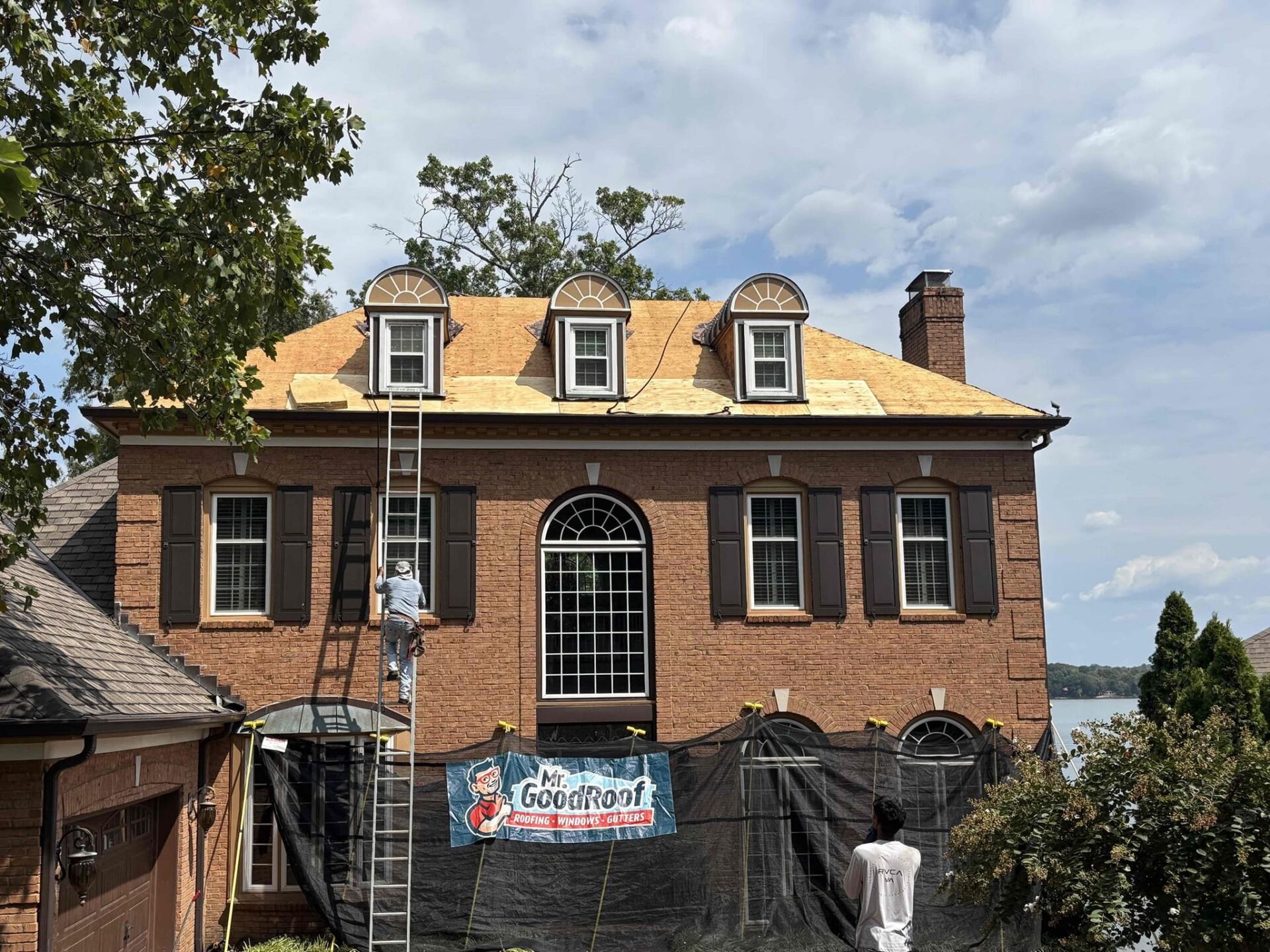 Two men in a white van that is covered in graphics for Mr Good Roof.