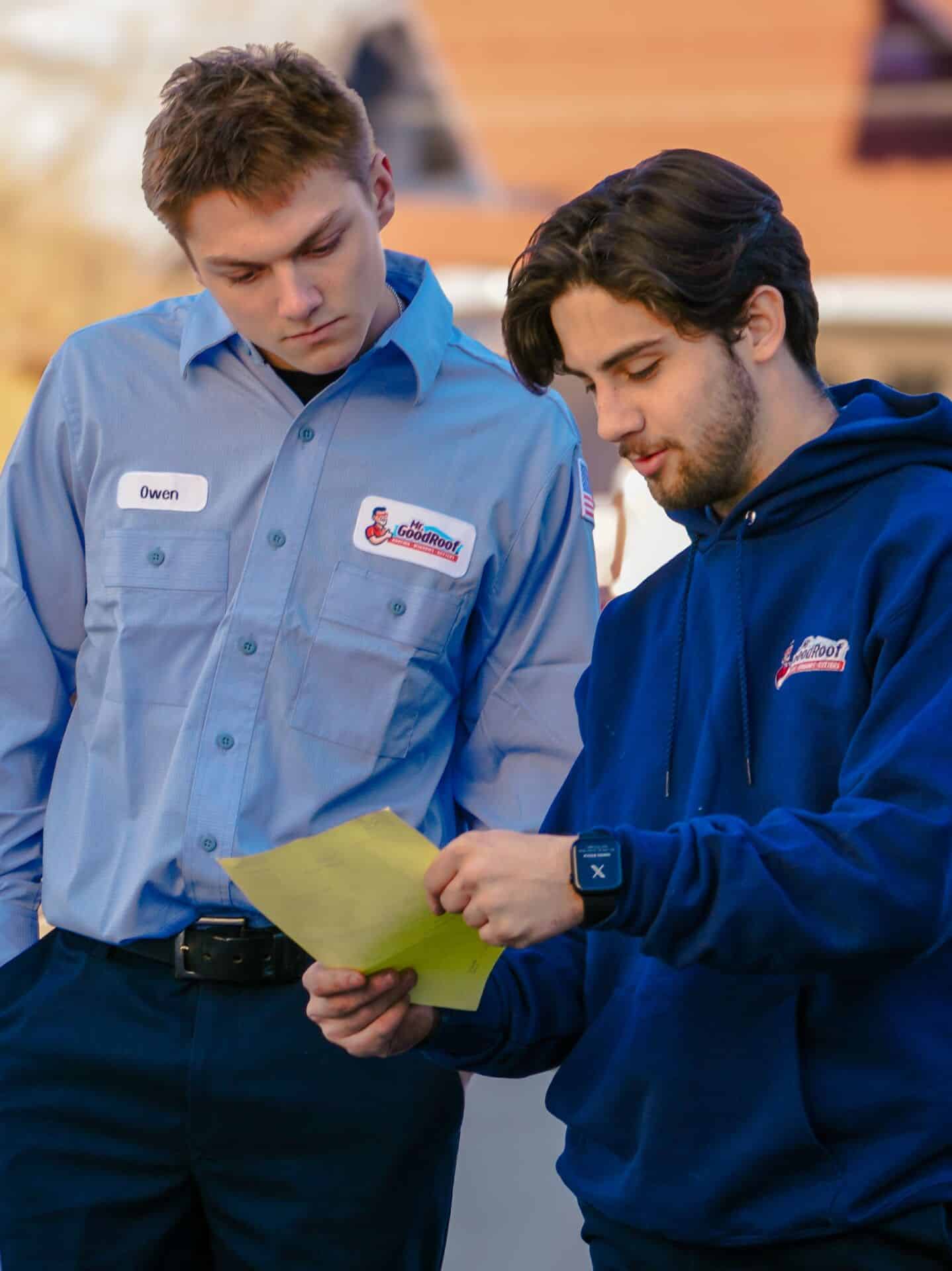 Two mr goodroof technicians looking over a plan for roofing services