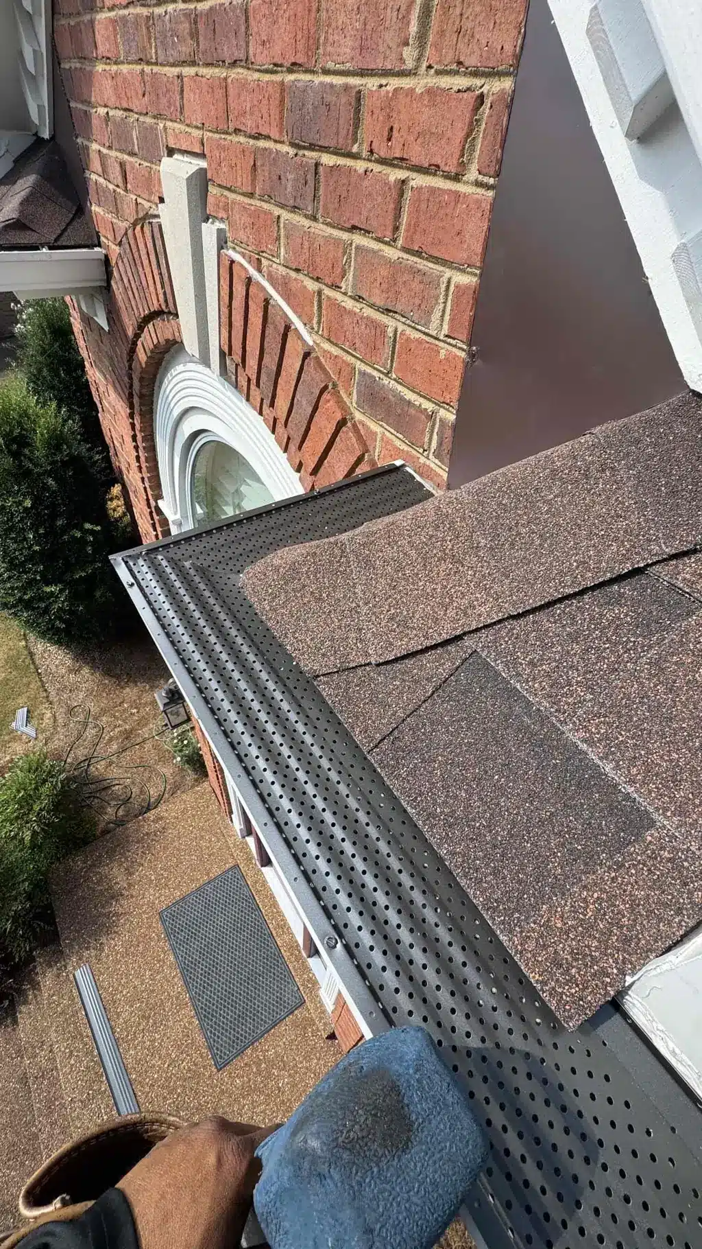 Perforated Bulldog gutter screen fitted around a corner beside brown architectural shingles.