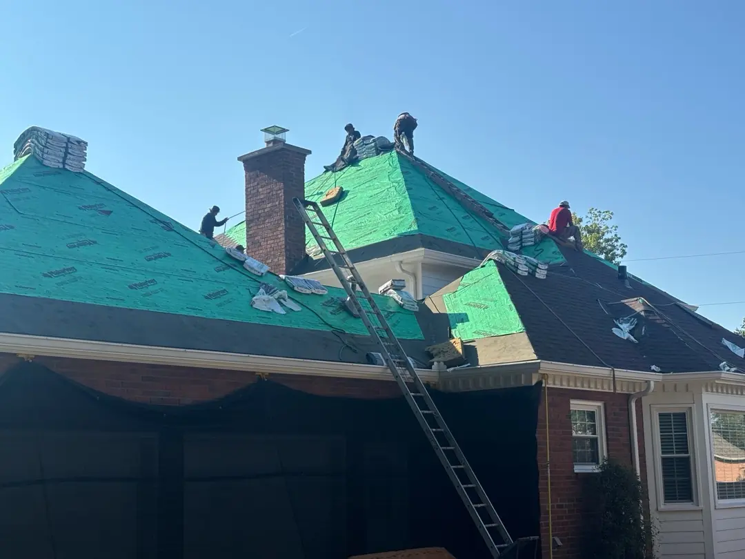 Roofing crew installing shingles over green underlayment on the Hendersonville home.
