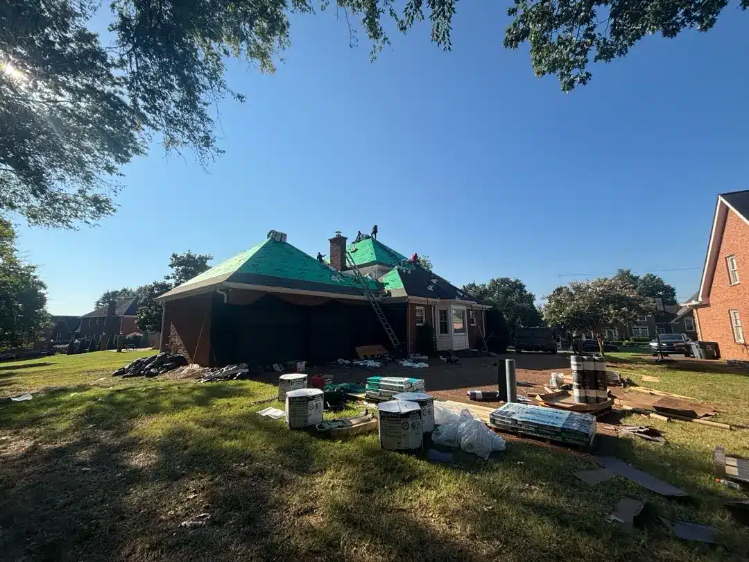 Wide view of the roof replacement in progress with materials arranged beside the home.