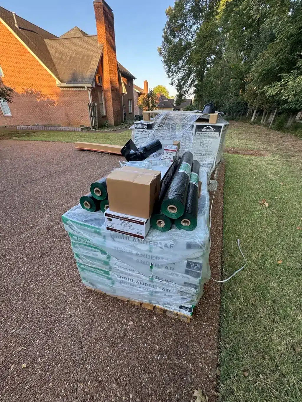 Highlander AR shingle bundles and roofing supplies staged at the Hendersonville property.